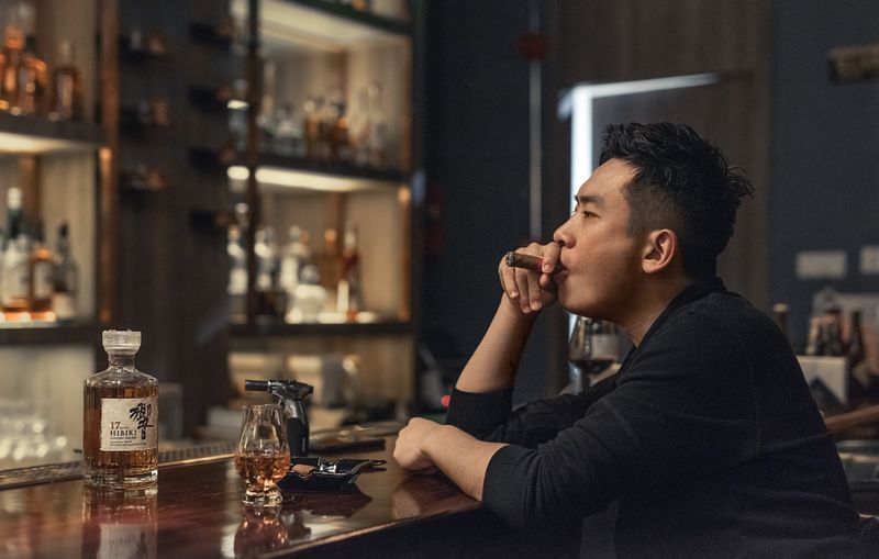 Guest savoring a premium cigar and whiskey at the lounge bar