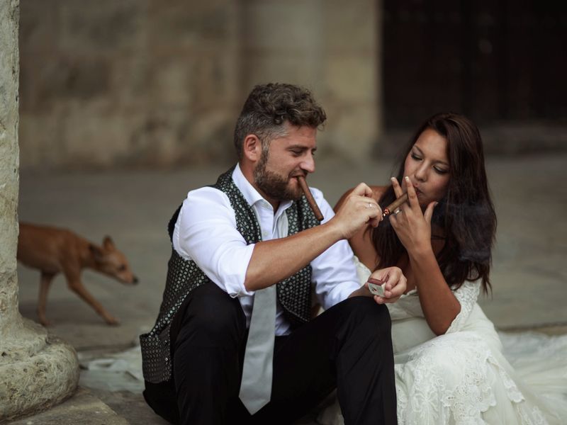 Bride and groom sharing cigars on their wedding day